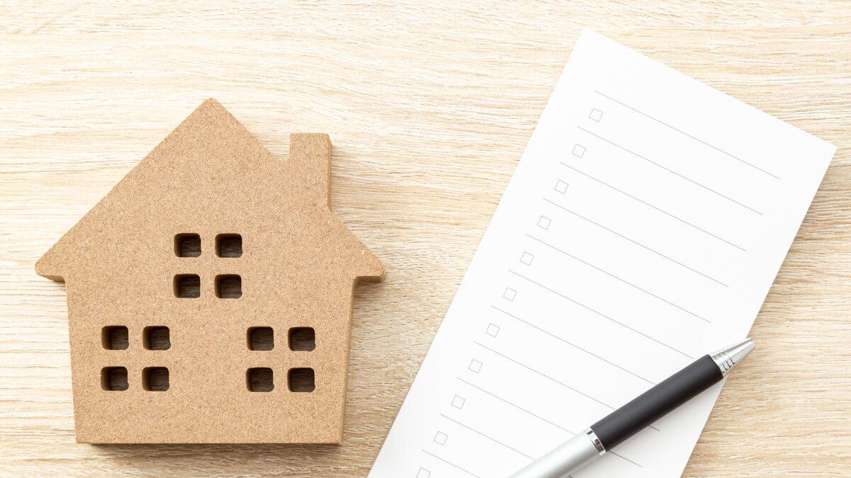 Cut out cardboard house next to notepad and pen